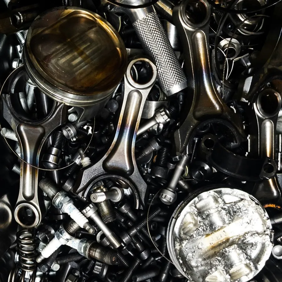 Heap of scrap engine and drivetrain parts: pistons, connecting rods, bolts and housings